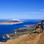 Spain, Canary Islands, Female Backpacker Hiking Along Edge Of Coastal Cliff Of La Graciosa Island Model Released Symbolf